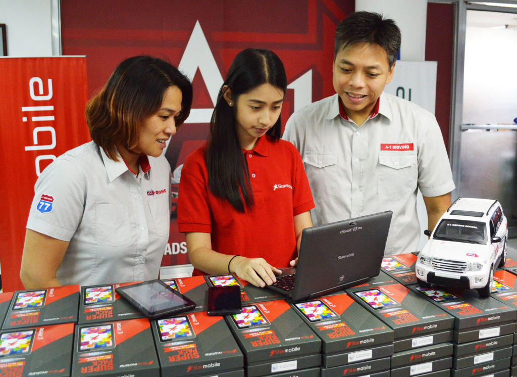 Vikha Vargas of Starmobile Marketing (center) demos the ENGAGE 10 Pro 2-in-1 Windows Tablet, UP Snap Android Smartphone, and ENGAGE 7i Android Tablet to A1 Driving School Business Development Head Luna Garcia (left) and AVP Aljun Garcia (right)