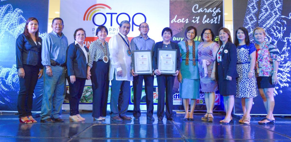 The DTI-Bureau of Domestic Trade Promotion (BDTP) awarded Certificates of Accreditation to the OTOP TindahangPinoy stores in Butuan City. These are operated by the CARAGA Regional Association of Traders & Entrepreneurs in Food, Inc. (CReATE Food Inc.). Receiving the certificates are Kevin Uy, OTOP TindahangPinoy-Butuan operations manager, and Esther Uy, CReATE Food Inc. president (sixth and seventh from left, respectively), with other CReATE Food officers. Presenting the certificates are DTI-BDTP assistant director Marievic Bonoan (fourth from left); DTI-Caraga regional director Brielgo Pagaran (fifth from left); and DTI-Industry Promotions Group undersecretary Nora Terrado (fifth from right).